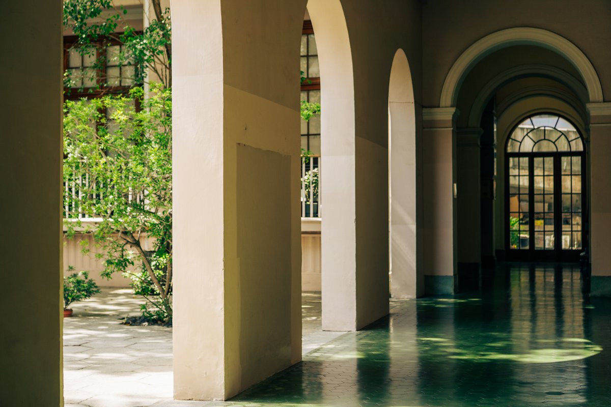 Sunlit arched corridor opening onto a green courtyard
