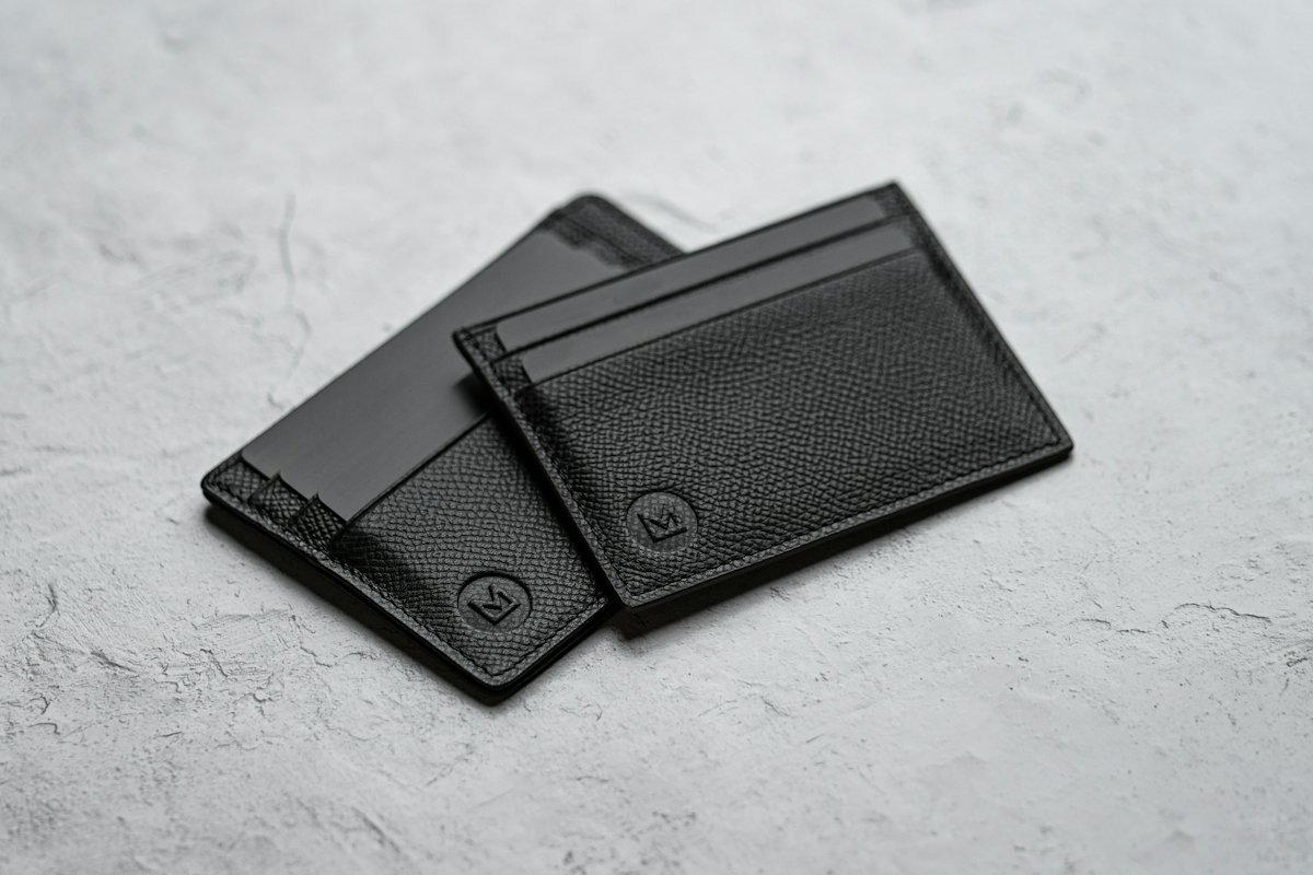 Two black leather card holders on stone