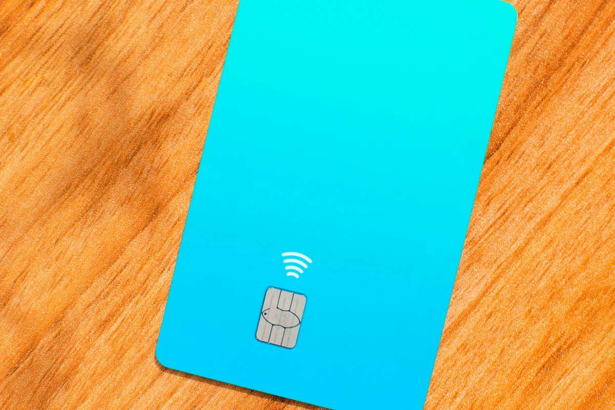 Plain turquoise contactless bank card on a wooden table