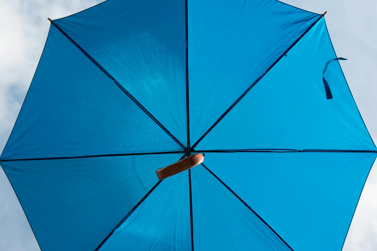 Open blue umbrella against a pale sky