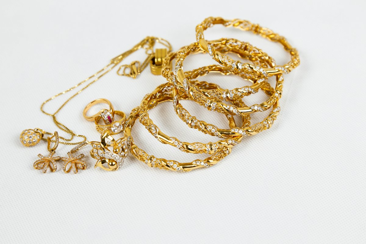 Gold bangles and necklaces on white