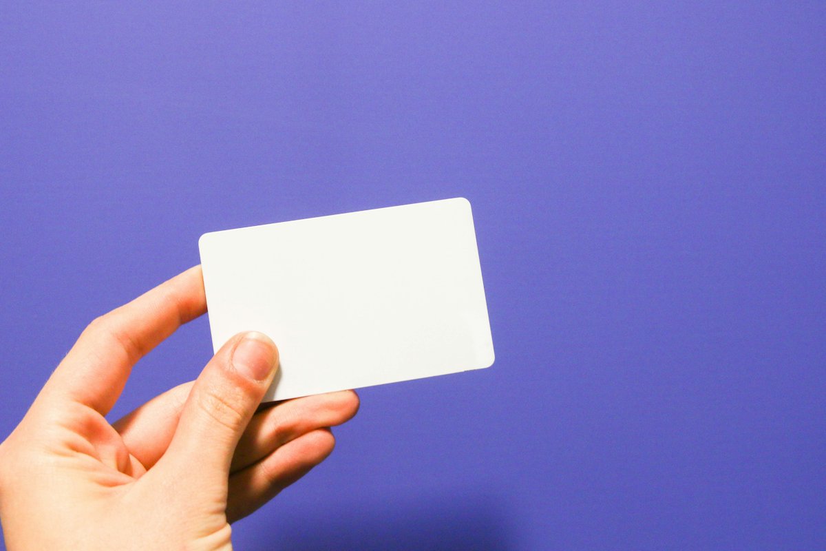 Hand holding a blank white card on a violet background