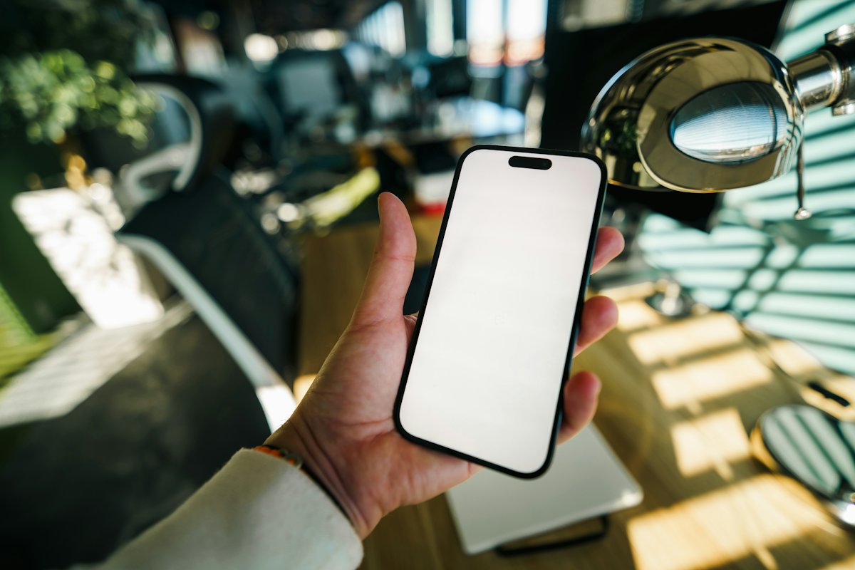 Hand holding a phone with a blank white screen
