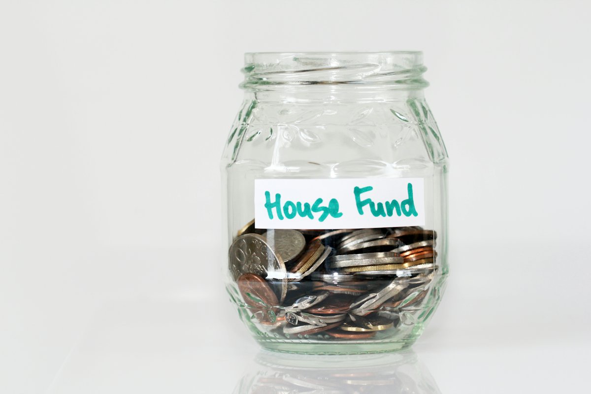 Glass savings jar filled with coins on a white background