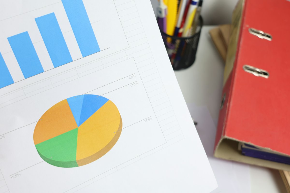 Printed bar and pie charts beside a red folder