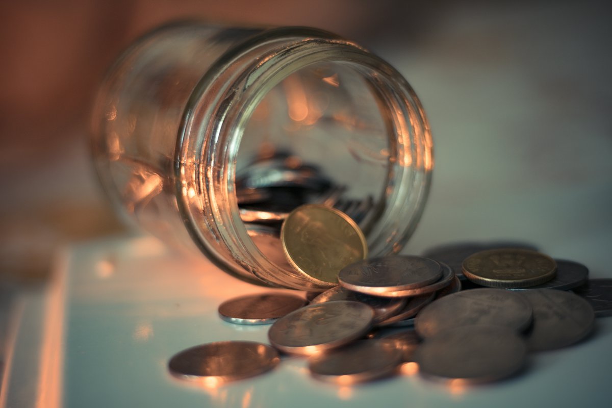 Coins spilling from a tipped glass jar