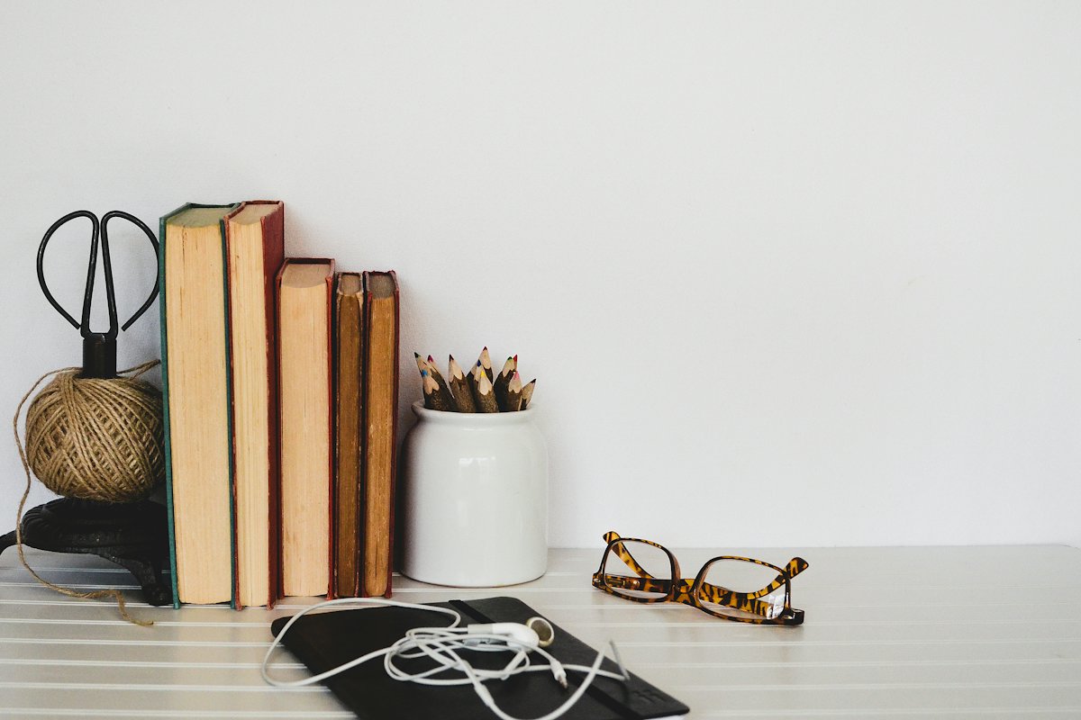 Stacked books and stationery on a white desk