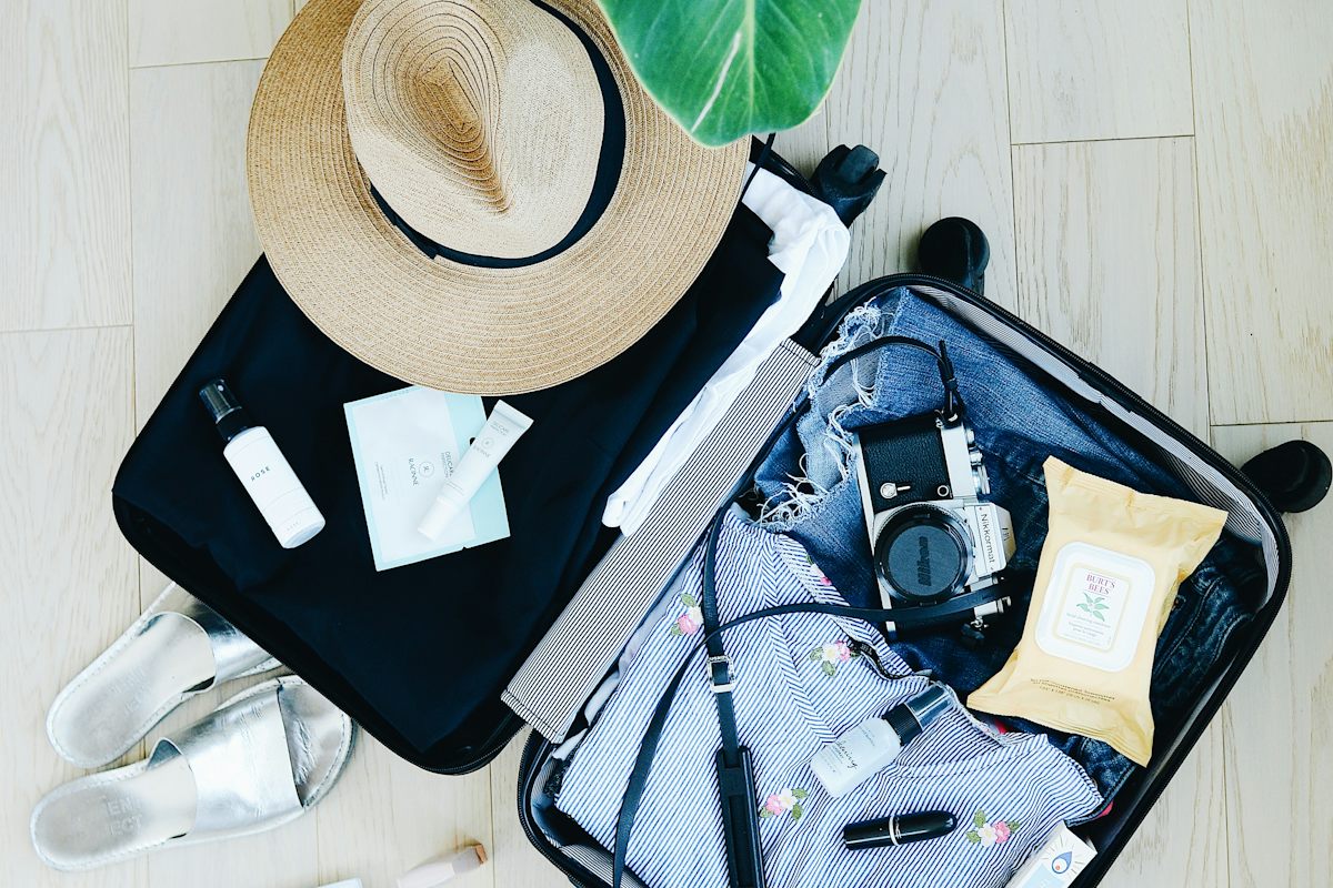Open suitcase packed with a hat and travel items