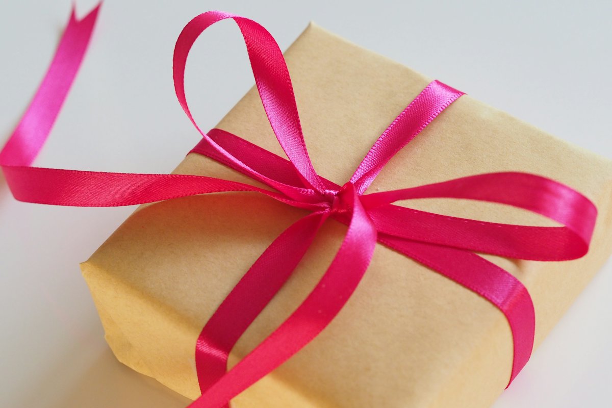 Gift box wrapped in kraft paper with a pink ribbon